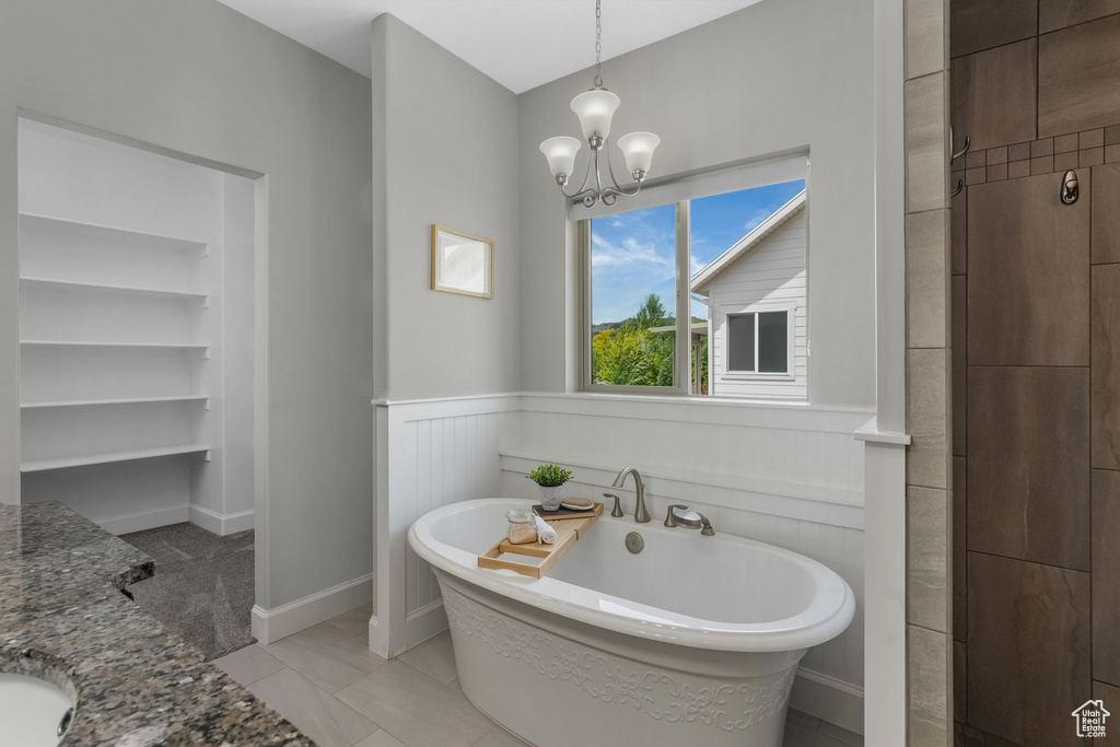 Bathroom with a freestanding tub, a chandelier, wainscoting, and vanity