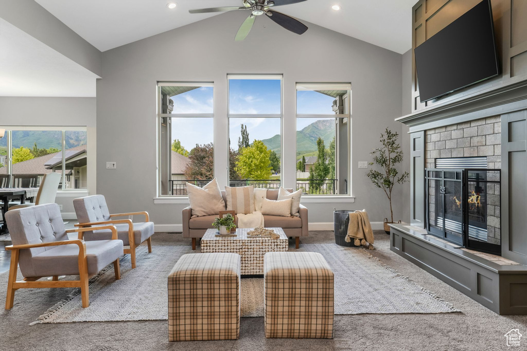 Carpeted living room featuring ceiling fan, vaulted ceiling, a fireplace, baseboards, and recessed lighting