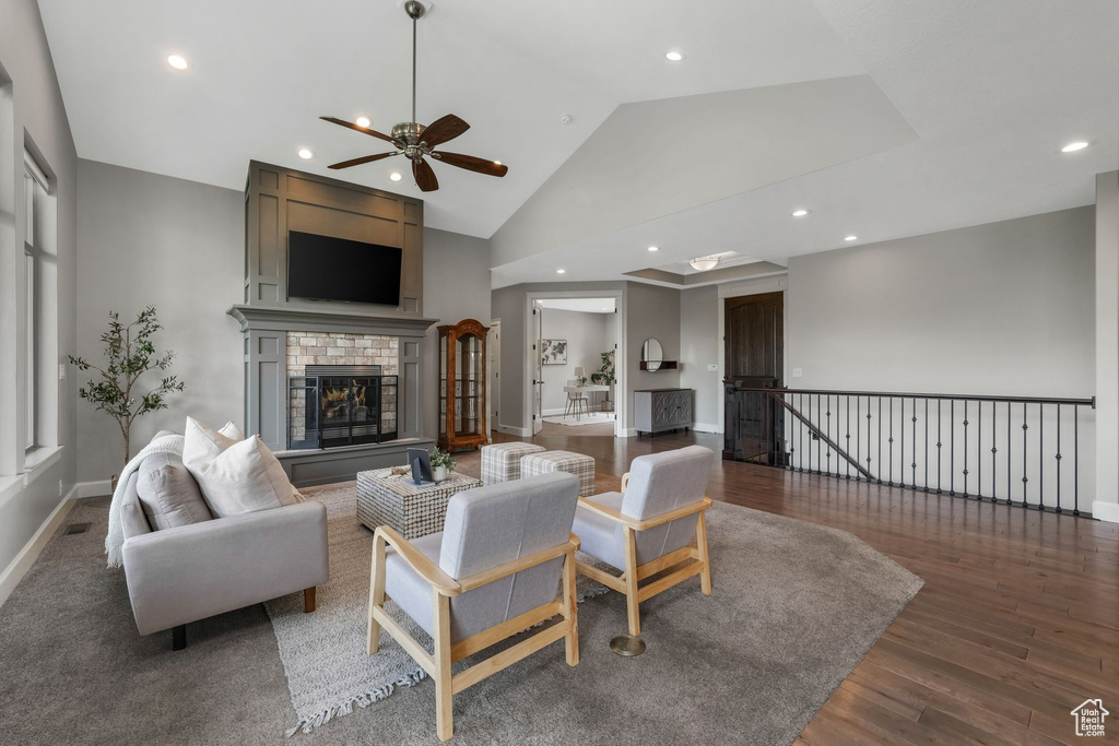 Living room with ceiling fan, wood finished floors, recessed lighting, baseboards, and a brick fireplace