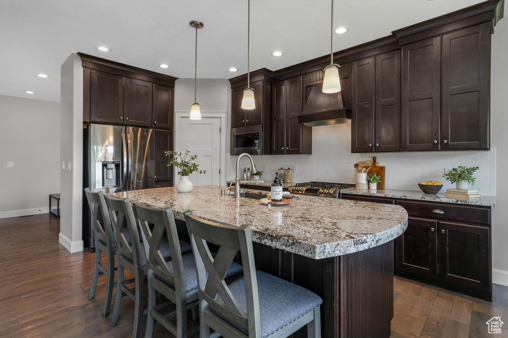 Kitchen featuring stainless steel appliances, baseboards, dark wood-type flooring, decorative backsplash, and recessed lighting