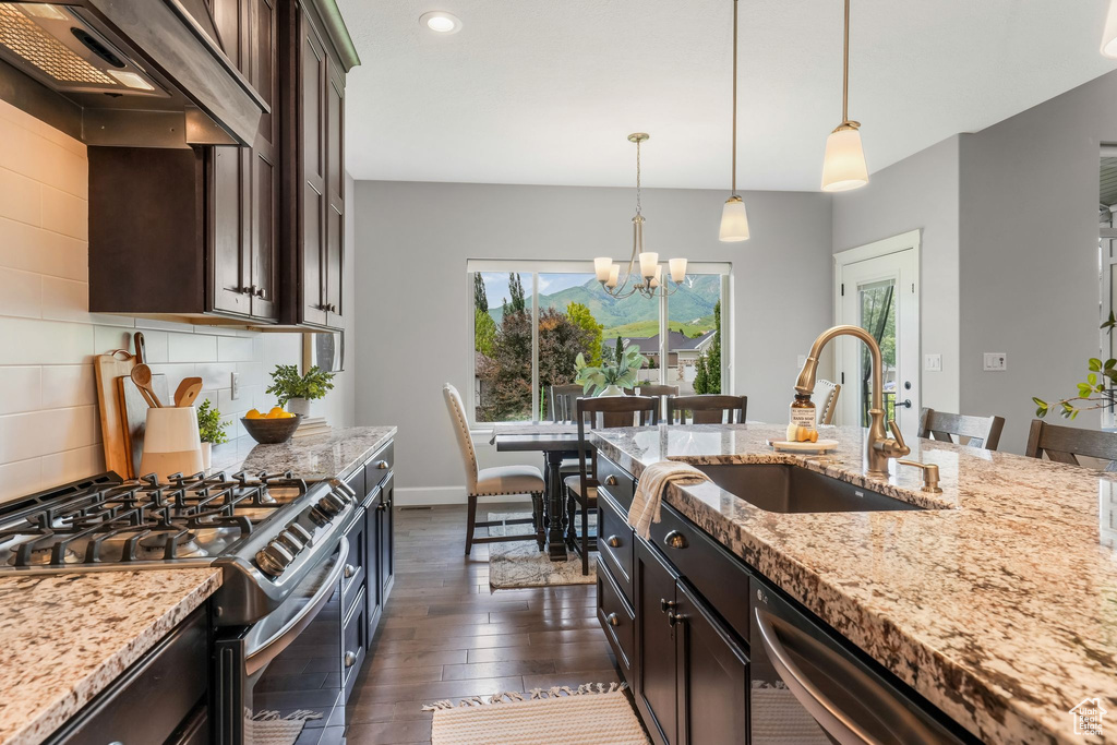 Kitchen featuring appliances with stainless steel finishes, a sink, custom range hood, tasteful backsplash, and dark brown cabinetry