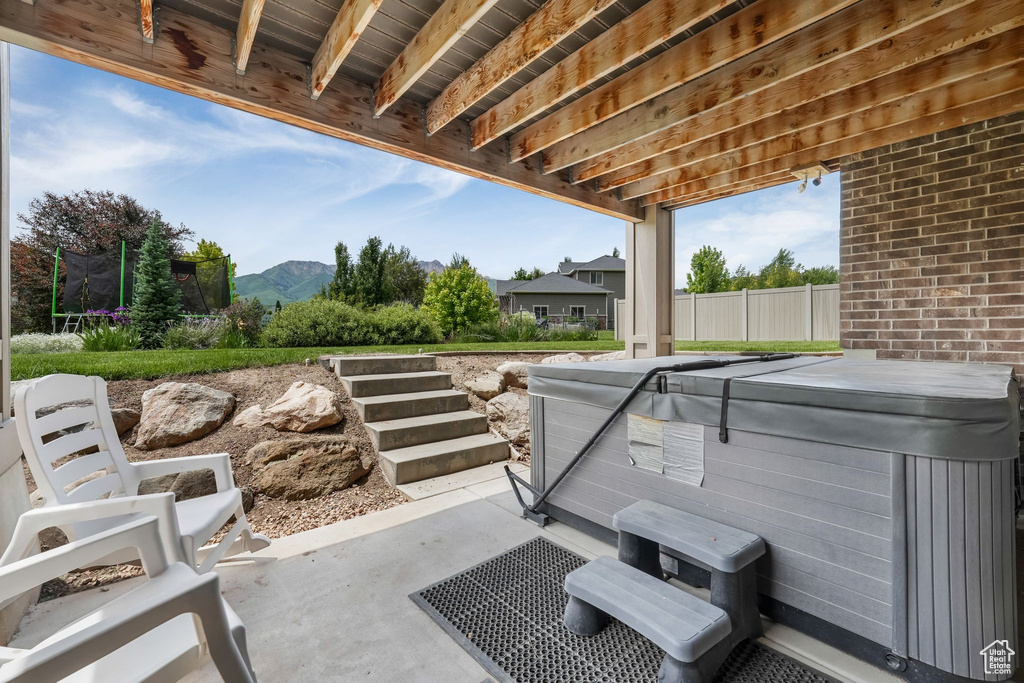 View of patio / terrace featuring a hot tub, a trampoline, and a mountain view