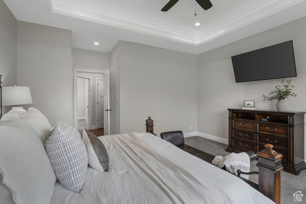 Carpeted bedroom with a tray ceiling, recessed lighting, crown molding, baseboards, and ceiling fan