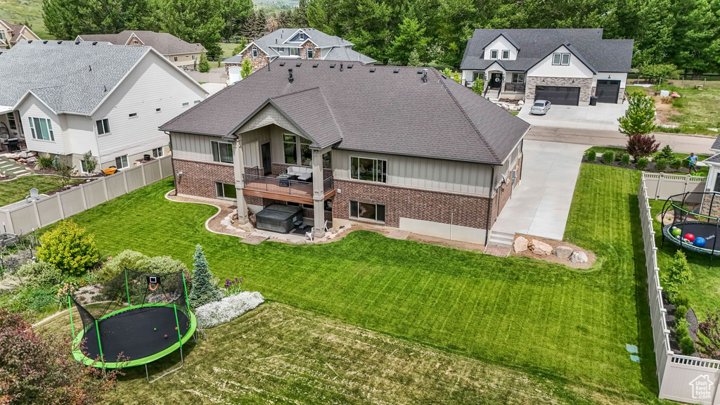 Back of house featuring a trampoline, brick siding, a covered hot tub, and a patio