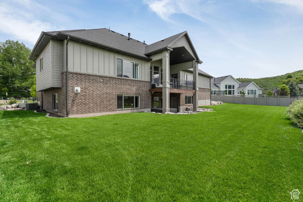 Back of property featuring a balcony, board and batten siding, brick siding, and roof with shingles