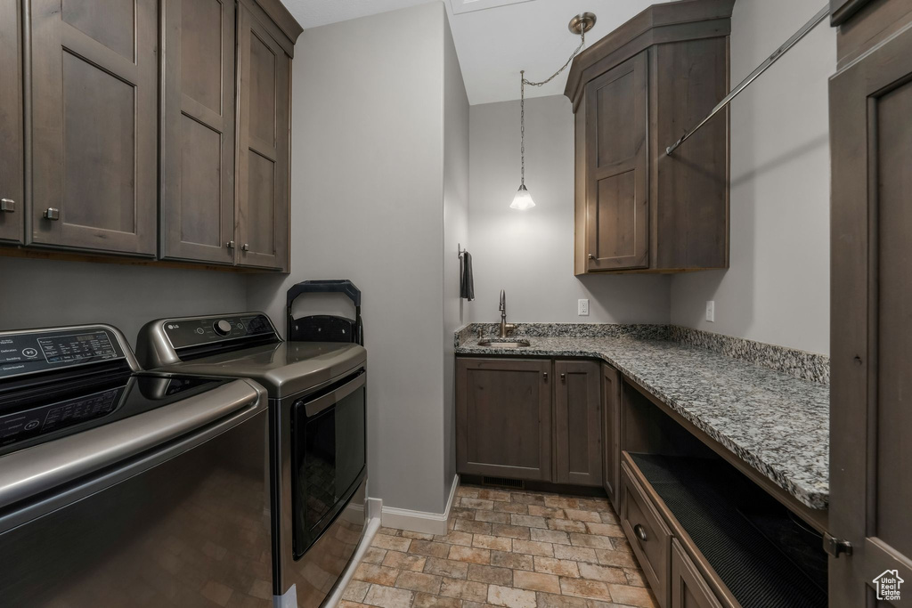 Washroom featuring independent washer and dryer, light stone finish floors, cabinet space, and baseboards