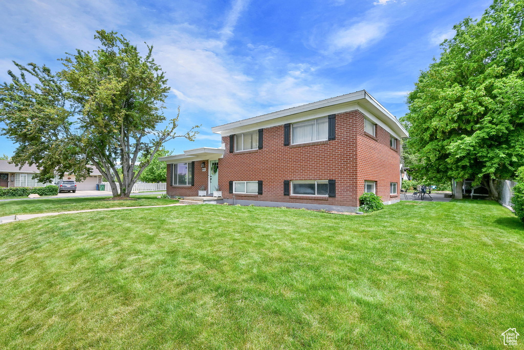 Tri-level home with a front yard and brick siding