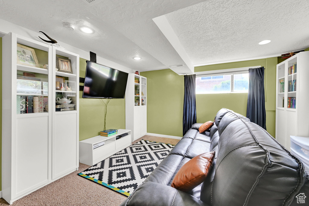Carpeted living area with a textured ceiling, recessed lighting, and baseboards