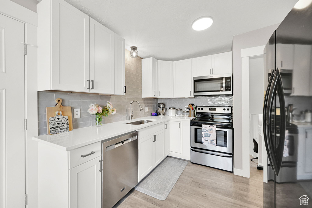 Kitchen featuring stainless steel appliances, a sink, tasteful backsplash, and light countertops