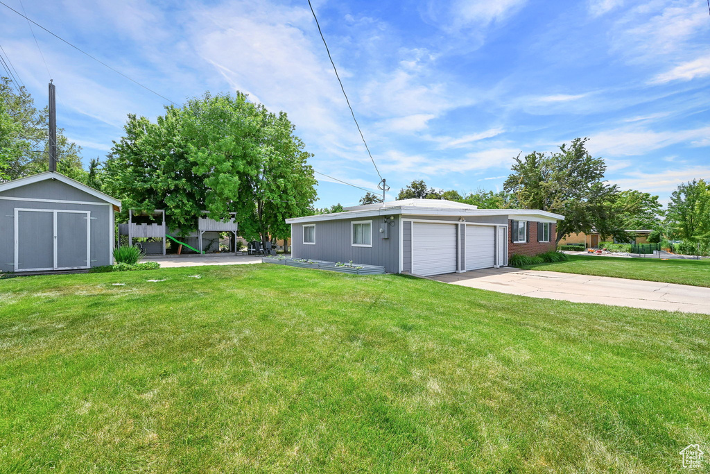 View of grassy yard with driveway and a garage
