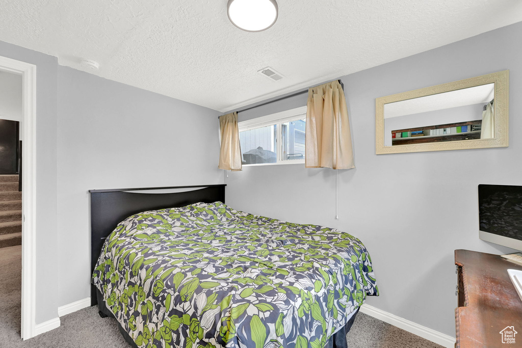 Bedroom featuring carpet floors, a textured ceiling, and baseboards