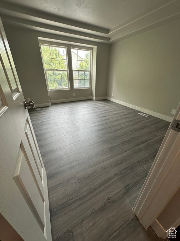 Empty room featuring dark wood finished floors and baseboards