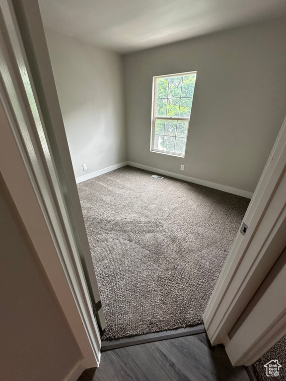 Unfurnished room featuring baseboards and dark colored carpet
