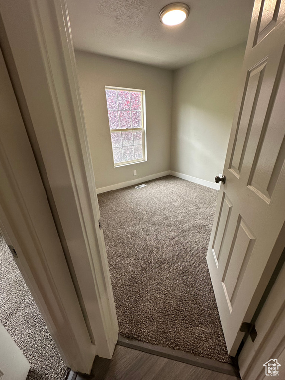 Spare room featuring dark carpet and baseboards