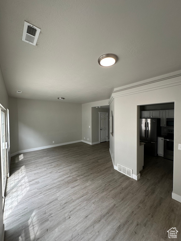 Unfurnished living room featuring baseboards, dark wood-style flooring, and a textured ceiling