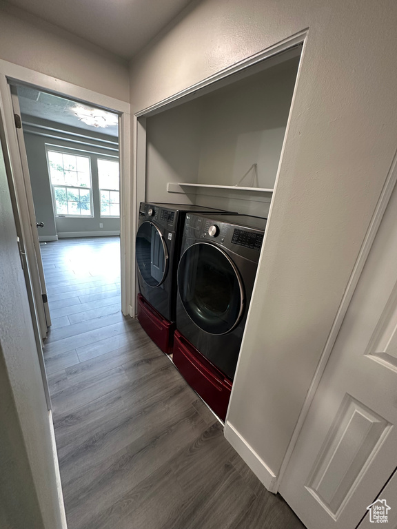 Laundry area with separate washer and dryer, wood finished floors, and baseboards