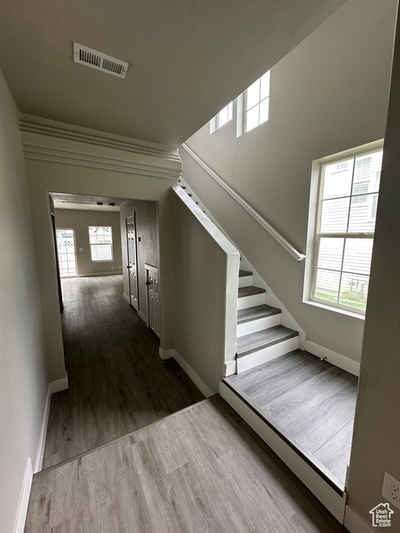 Corridor with wood finished floors, baseboards, and stairs