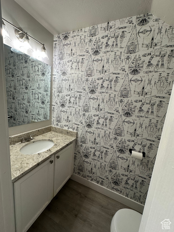 Bathroom featuring wood finished floors, vanity, toilet, and baseboards