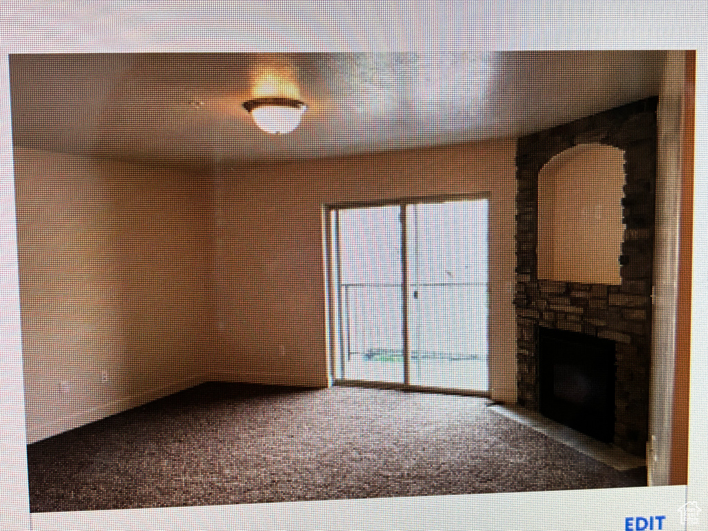 Unfurnished living room featuring carpet flooring and a fireplace