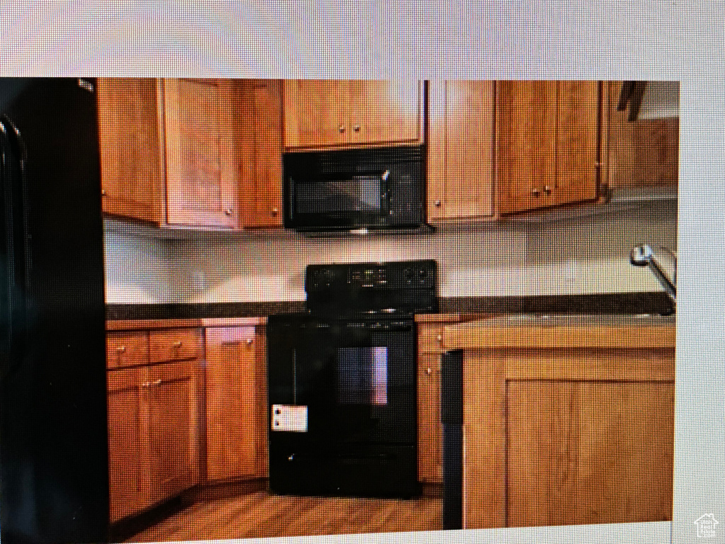 Kitchen featuring black / electric stove, dark countertops, tasteful backsplash, and brown cabinetry