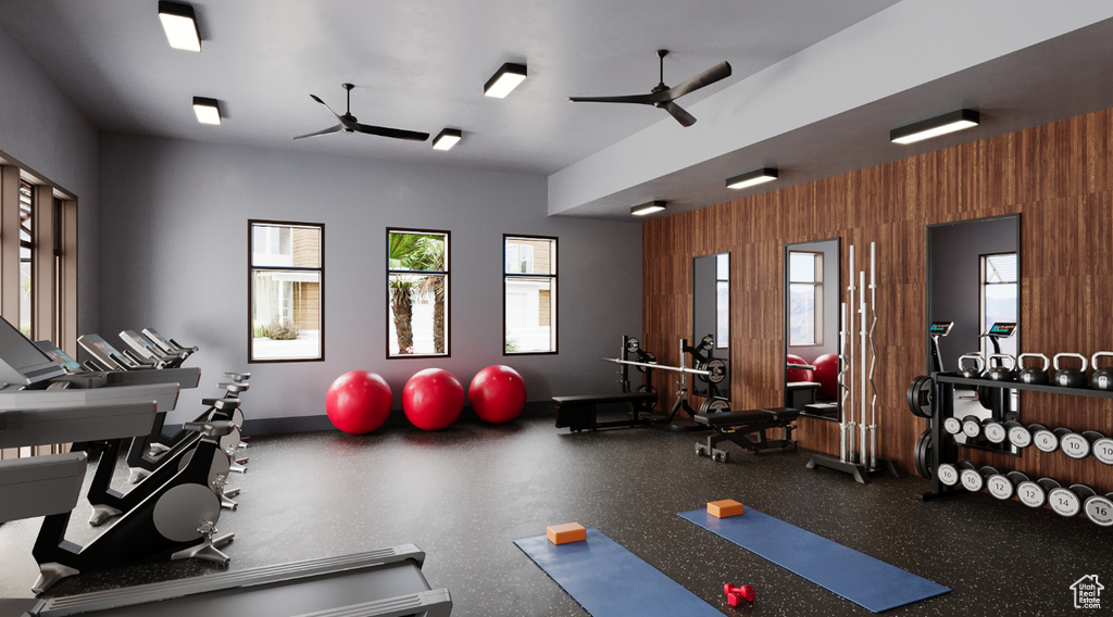 Workout area with ceiling fan, wood walls, and baseboards