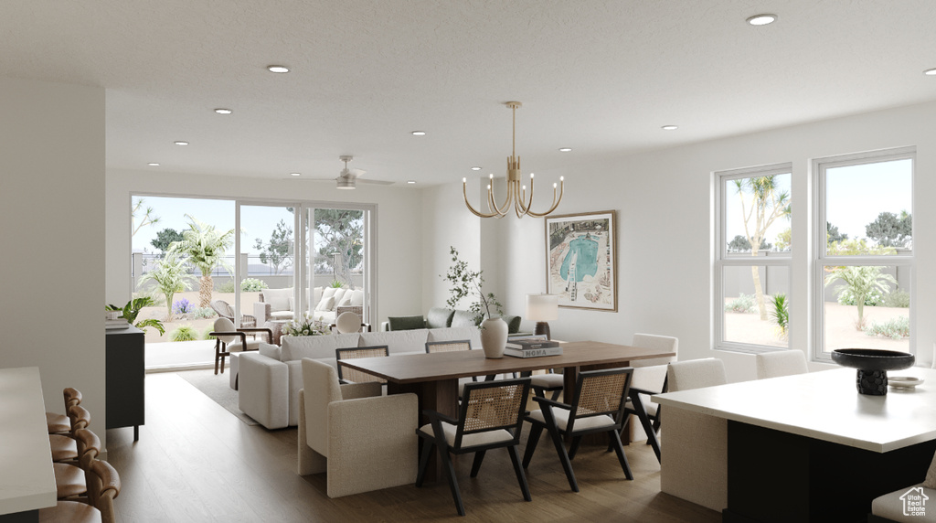 Dining room featuring wood finished floors, healthy amount of natural light, recessed lighting, and a chandelier