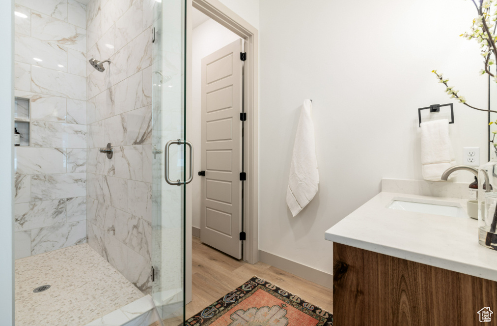 Bathroom featuring vanity, a stall shower, wood finished floors, and baseboards