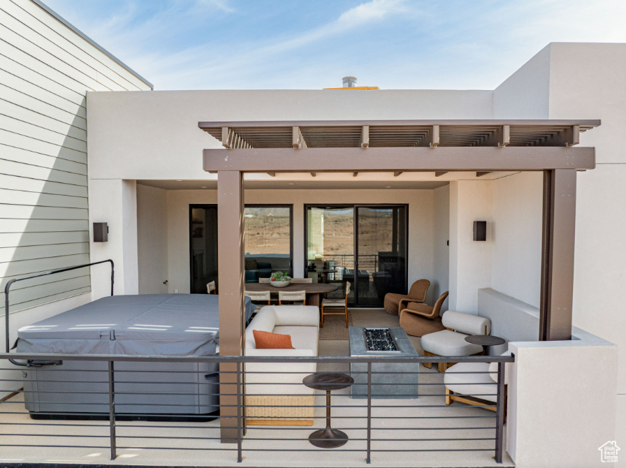View of patio with a balcony, a hot tub, and an outdoor living space with a fire pit