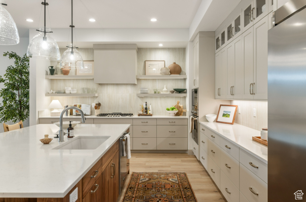 Kitchen with stainless steel appliances, open shelves, light countertops, a sink, and recessed lighting