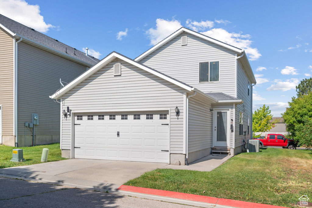 Traditional-style house with central air condition unit, a front yard, driveway, and a garage