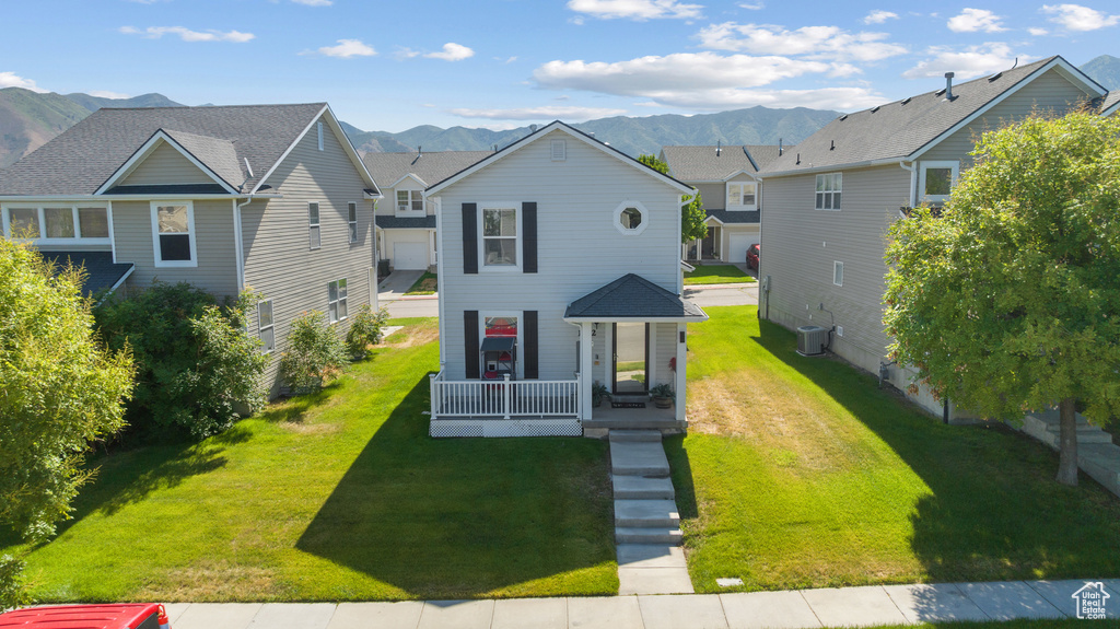 View of front of house featuring central air condition unit, a mountain view, and a front lawn
