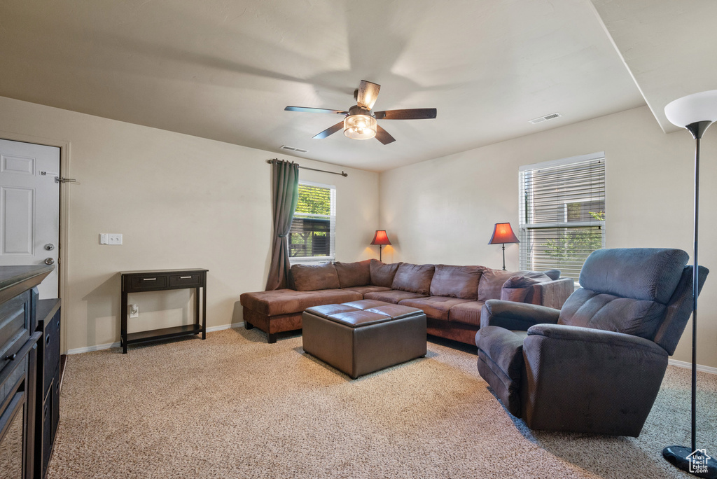 Living area featuring ceiling fan, light carpet, and baseboards