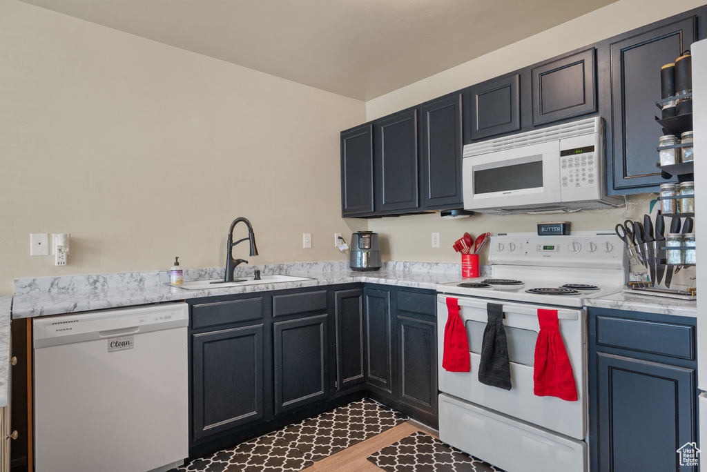Kitchen featuring white appliances, a sink, and light countertops