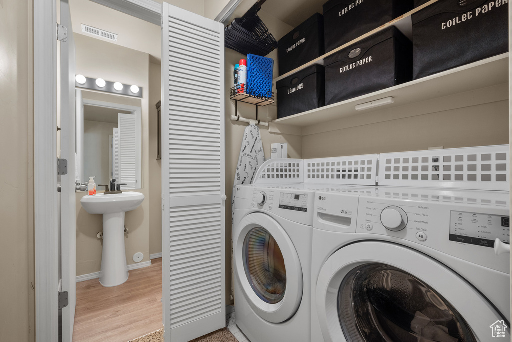 Laundry area with baseboards, wood finished floors, and washer and dryer