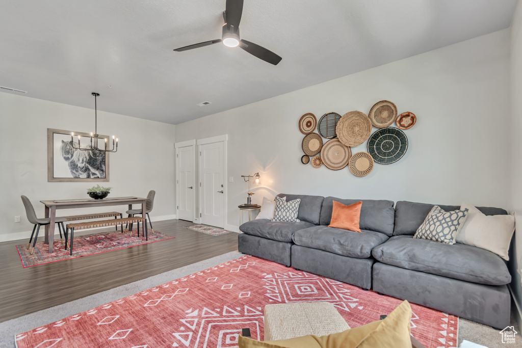 Living area featuring a chandelier, a ceiling fan, baseboards, and wood finished floors