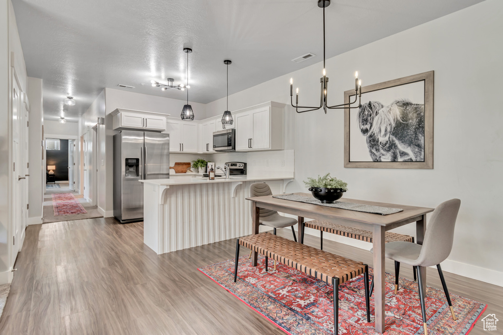 Dining space with a chandelier, baseboards, and light wood-style flooring