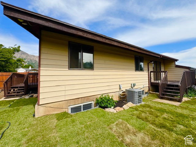 View of home's exterior featuring a deck with mountain view, central air condition unit, and a lawn