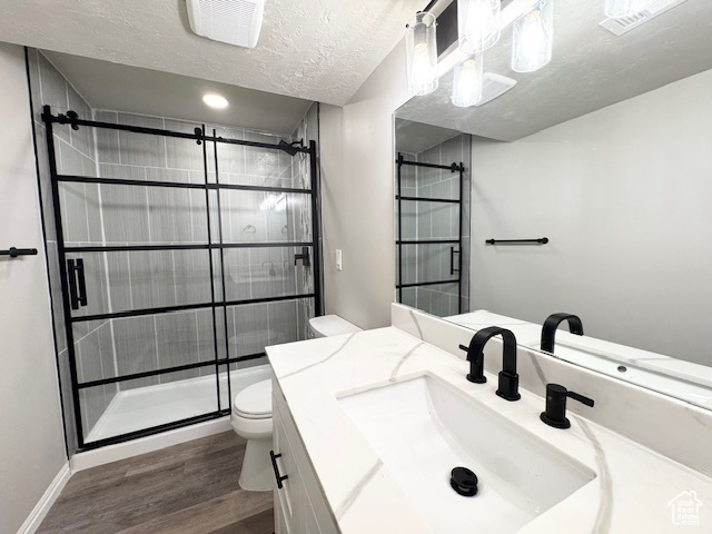 Full bathroom featuring toilet, wood finished floors, a stall shower, vanity, and baseboards