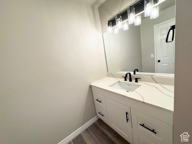 Bathroom featuring wood finished floors, vanity, and baseboards