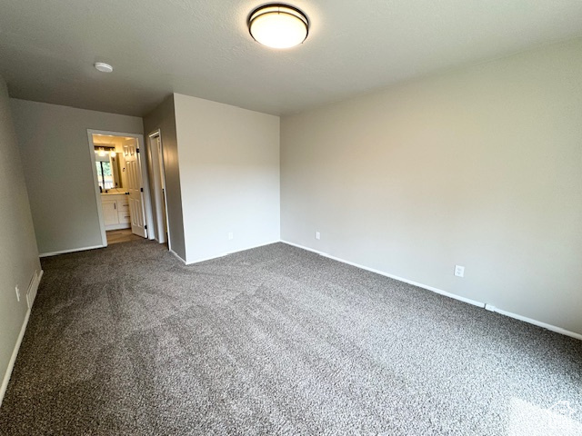 Empty room featuring dark colored carpet and baseboards