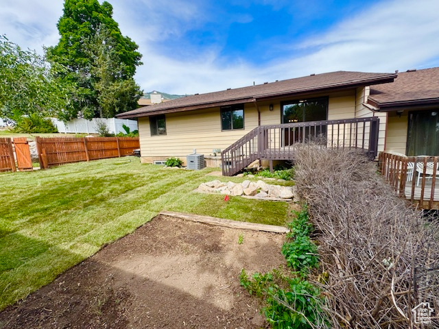 Rear view of property featuring central air condition unit and a wooden deck