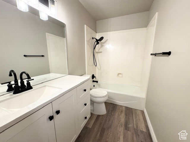 Bathroom featuring wood finished floors, toilet, vanity, and shower / bath combination