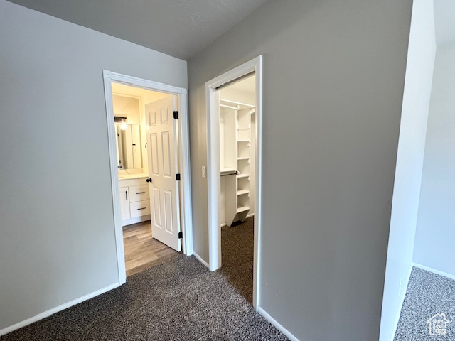 Hallway featuring dark carpet and baseboards