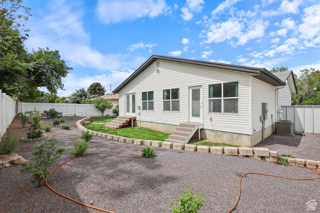 Rear view of property featuring entry steps, cooling unit, and a fenced backyard