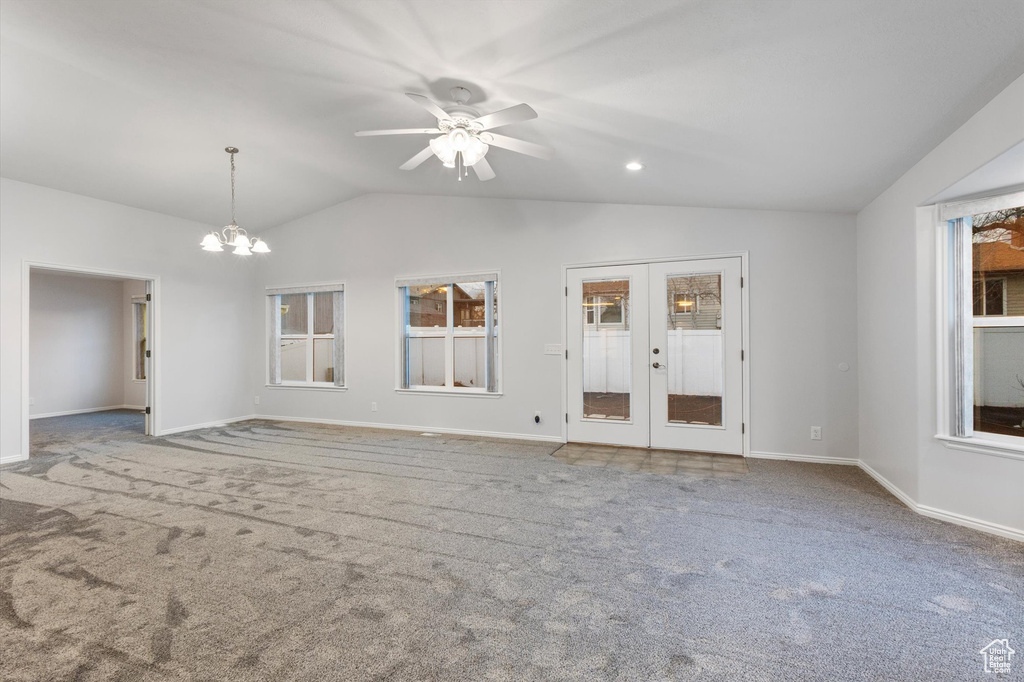 Unfurnished living room featuring lofted ceiling, carpet floors, french doors, baseboards, and a chandelier