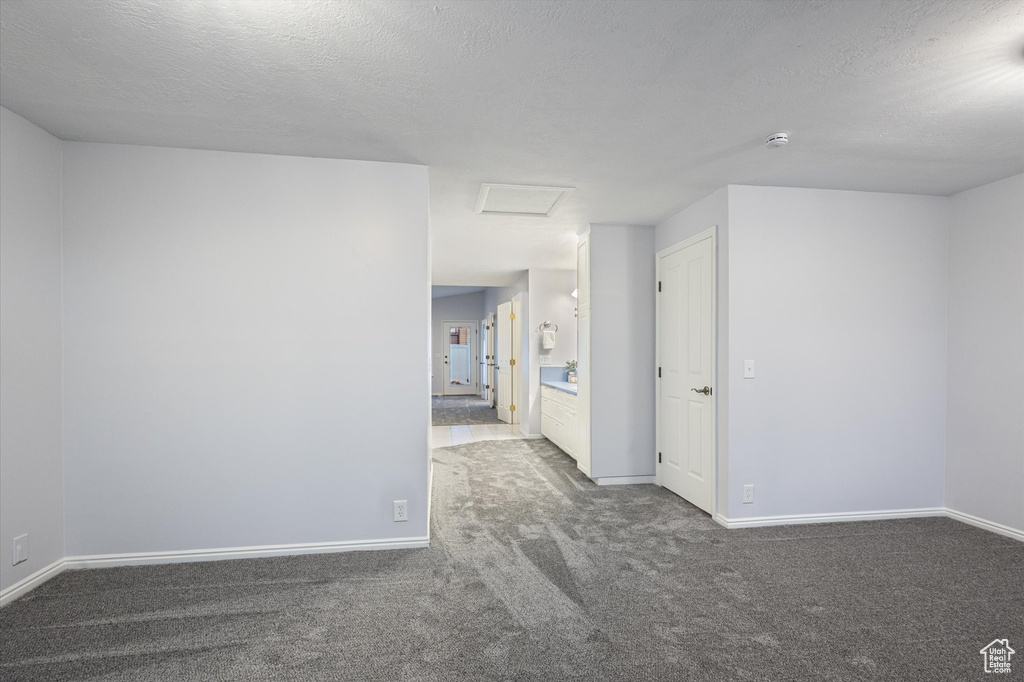 Carpeted empty room with attic access, baseboards, and a smoke detector