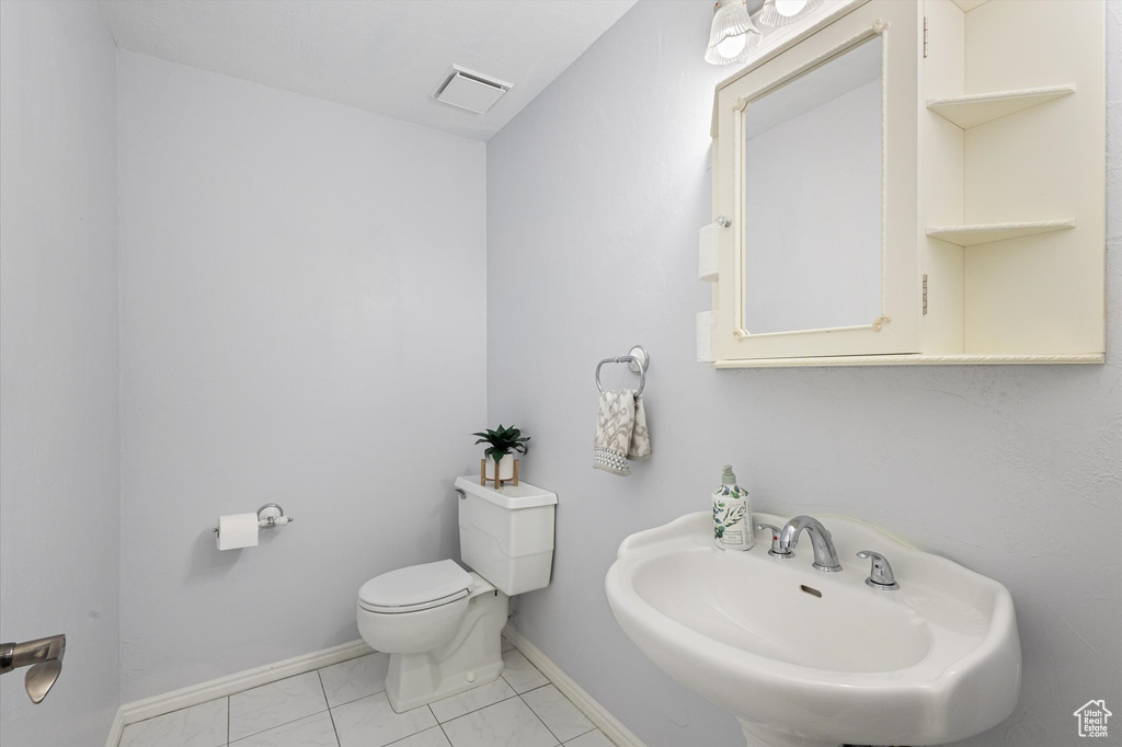 Bathroom featuring a sink, toilet, baseboards, and tile patterned flooring
