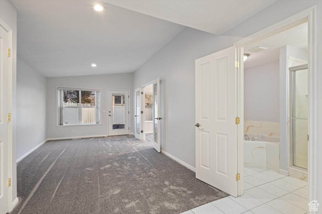 Interior space featuring lofted ceiling, recessed lighting, baseboards, carpet floors, and tile patterned floors