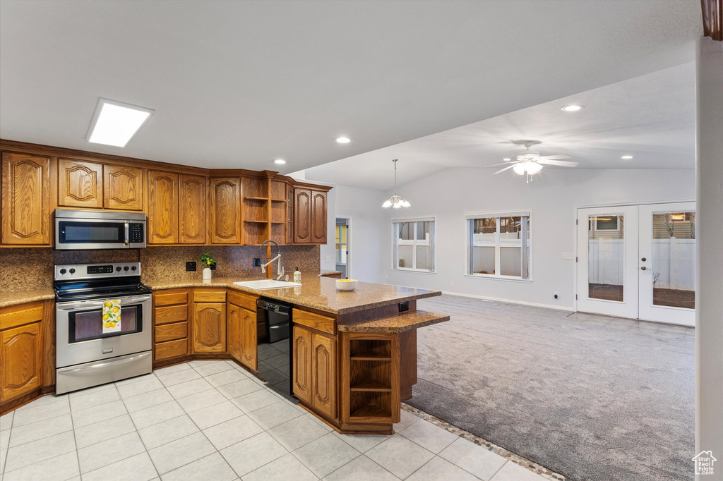 Kitchen with open shelves, stainless steel appliances, brown cabinetry, a sink, and light carpet