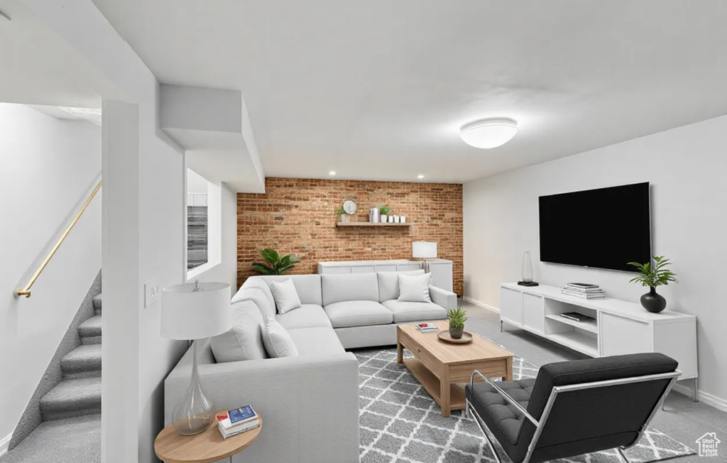Living room with brick wall, stairs, baseboards, light carpet, and recessed lighting
